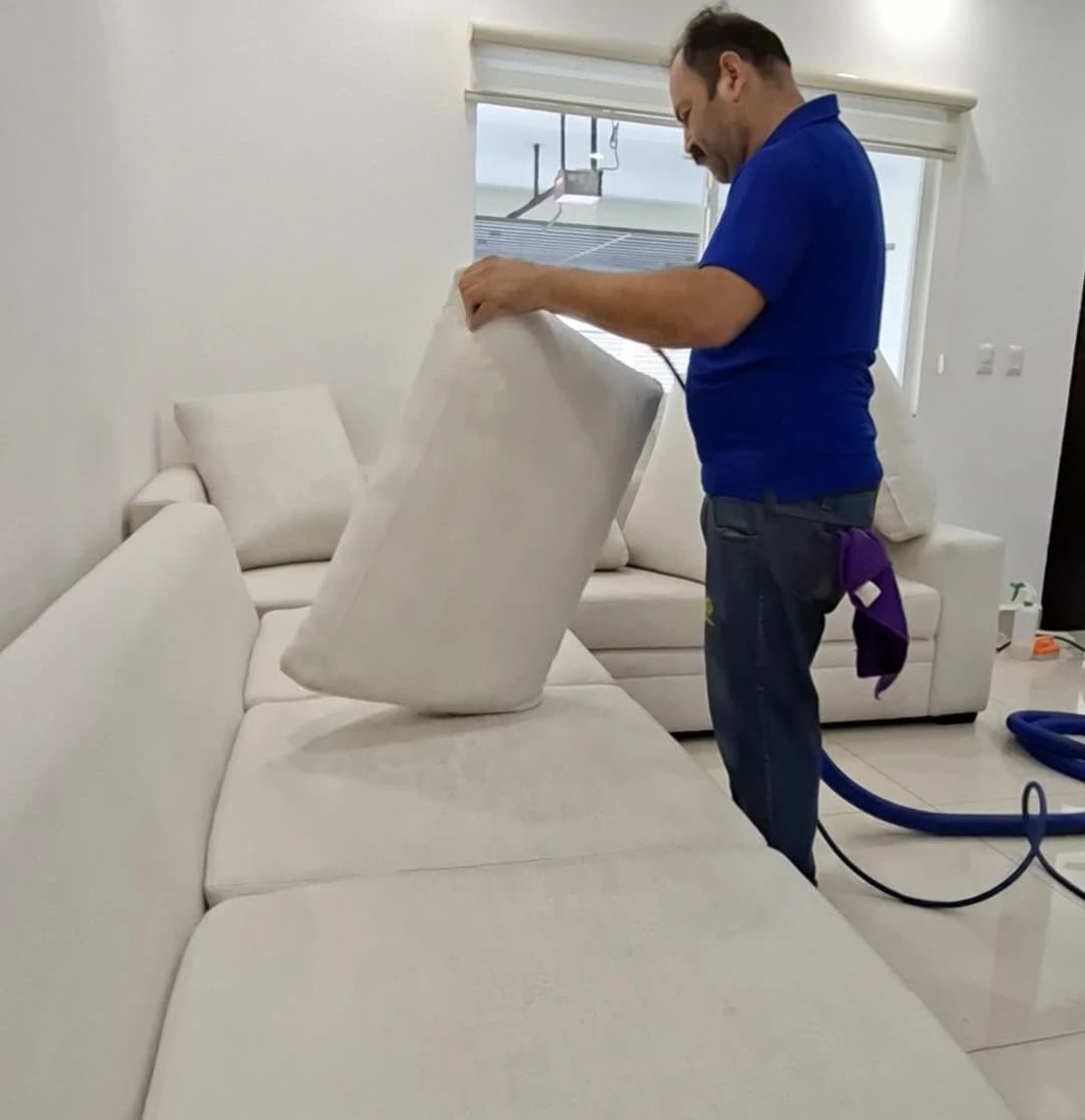 Técnico de Lavado Real aplicando limpieza profunda en tapicería de sala en domicilio